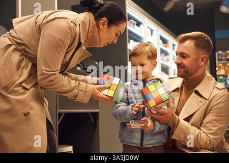Die Familie ist im Spielwarenladen und hält Rubiks Würfel. Stockfoto