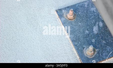 Nahaufnahme einer strukturierten Betonoberfläche mit einer Metallplatte und Schrauben Stockfoto