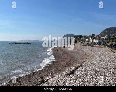 Die Leute saßen am Strand von Sidmouth in Devon Stockfoto
