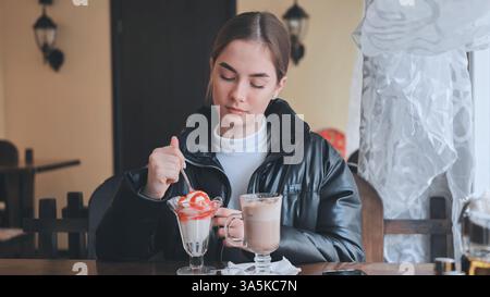 Die Person genießt süße Leckereien und schlürft warmes Getränk am rustikalen Kaffeetisch Stockfoto