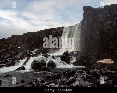 Öxarárfoss Wasserfall im Nationalpark Þingvellir, Island. Mächtige Kaskaden krachen über zerklüftete Vulkangesteine und erzeugen eine dramatische, stimmungsvolle Atmosphäre i Stockfoto