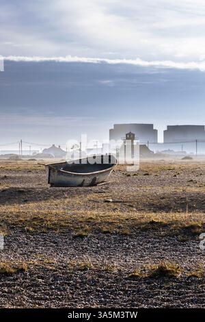 Verlassenes Boot an einem Kiesstrand mit Dungeness Power Station im Hintergrund, Dungeness, Kent, England Stockfoto