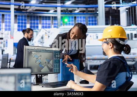 Teamkollegen in der Photovoltaik-Fabrik prüfen Systemprotokolle, um betriebliche Ineffizienzen zu identifizieren. Mann und Frau in Photovoltaik-Anlagen, die Herstellungsparameter einstellen Stockfoto