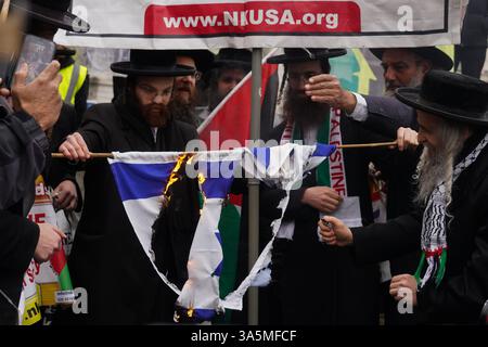 London, Vereinigtes Königreich. März 2025. Mitglieder der anti-zionistischen Haredi-jüdischen Gruppe Neturei Karta verbrennen die israelische Flagge, bevor sie mit Tausenden pro-Palästinensern vom Marble Arch zum Portland Place in der Nähe der BBC am Internationalen Al-Quds-Tag marschieren. Der internationale Al-Quds-Tag ist eine pro-palästinensische Veranstaltung am letzten Freitag des islamischen heiligen Monats Ramadan. Der Name leitet sich von dem arabischen Namen für Jerusalem ab. Kundgebungen finden am Quds-Tag in verschiedenen Ländern der muslimischen Welt sowie in nicht-muslimischen Gemeinden auf der ganzen Welt statt, um gegen die israelische Besatzung zu protestieren Stockfoto