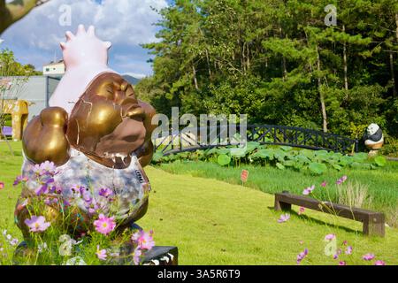 Muan County, Südkorea - 25. September 2020: Ein farbenfroher Skulpturenpark mit skurrilen Charakteren, mit einem ruhigen Teich mit Lotusblumen und einem Stockfoto