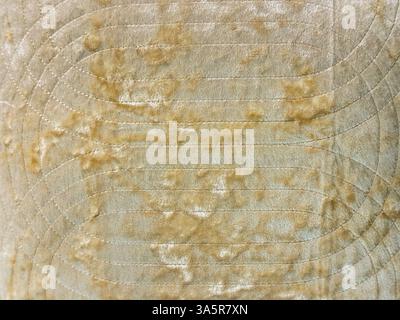 Nahaufnahme von dekorativem Stoff in Gold und Beige, zufälliger Grunge- und Schmutztextur. Nahtlose Hintergrundstruktur aus goldenem Stoff. Stockfoto