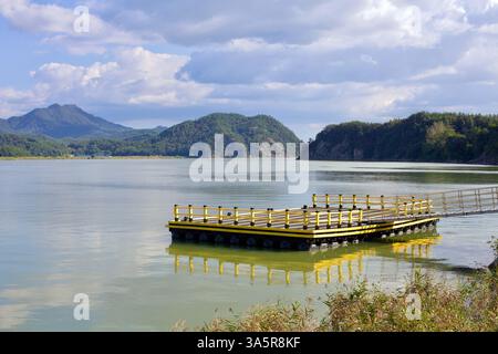 Muan County, Südkorea - 25. September 2020: Ein gelb lackiertes schwimmendes Dock erstreckt sich in den Yeongsangang River und bietet einen malerischen Blick auf das Surro Stockfoto