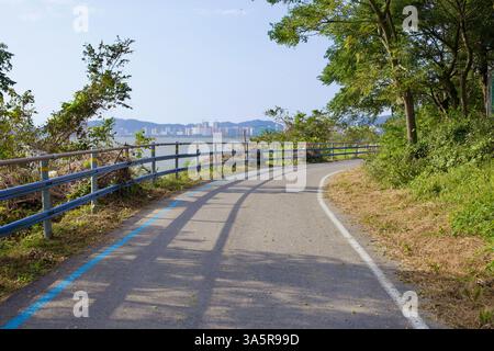 Muan County, Südkorea - 25. September 2020: Ein gewundener Abschnitt des Yeongsan River Bike Path folgt dem Fluss, eingerahmt von üppigem Grün, mit Stockfoto