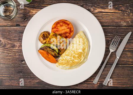 Rustikaler Frühstücksteller mit Spiegeleiern, gegrilltem Gemüse und putenspeck Stockfoto