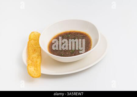 Dampfende heiße französische Zwiebelsuppe, serviert in einer weißen Schüssel mit goldgeröstetem Brot Stockfoto