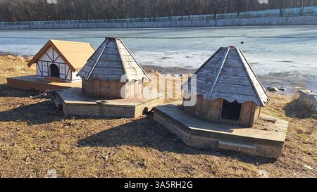 Hölzerne Entenhäuser am gefrorenen See in der Wintersonne Stockfoto