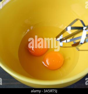 Nahaufnahme eines Paars roher Eier in der Mischschüssel wird geschlagen Stockfoto