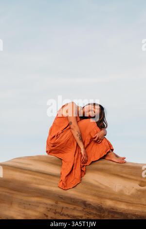 Junge Frau, die auf einem Sandsteinfelsen mit geschlossenen Augen ruht Stockfoto
