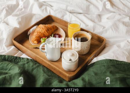 Frühstück im Bett - Holztablett mit Kaffee, Saft und Croissant Stockfoto