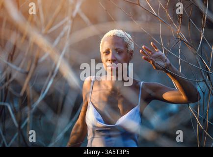 Porträt einer Frau in einem lila Kleid bei Sonnenuntergang im Wald Stockfoto