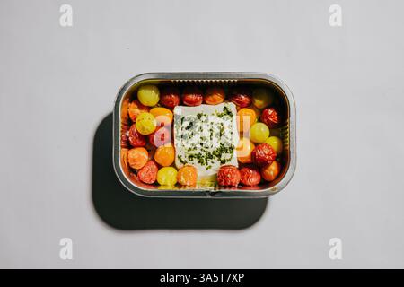 Ein kleiner Behälter mit Lebensmitteln mit einer Vielzahl von Obst und Gemüse. Der Behälter ist silber und hat einen Deckel Stockfoto