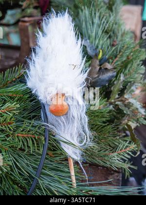 Stockholm, Schweden - 21. Dezember 2024: Eine skurrile Weihnachtsdekoration mit einem Zwerg mit flauschigem weißem Bart und orangener Nase, die auf dem Rücken steht Stockfoto