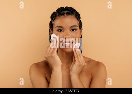 Hautpflegekonzept. Happy Beautiful Schwarzes Weibliches Reinigungsgesicht Mit Zwei Wattepads Stockfoto