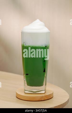 Eismatcha mit Milchschaum auf einem Holztisch. Eine perfekte Mischung aus Aromen und Texturen. Stockfoto