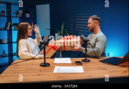 Zwei Personen sind im Podcast-Raum und halten Silvester-Geschenkboxen bereit. Stockfoto