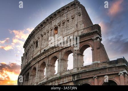 Das Kolosseum steht majestätisch, beleuchtet von einem warmen Sonnenuntergang. Steinbögen umrahmen das antike Bauwerk. Rom. Italien Stockfoto