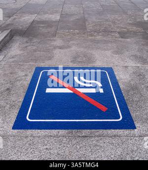 Ein Rauchverbot auf einer Betonoberfläche mit einer Zigarette mit einer roten Diagonallinie, die einen rauchfreien Bereich anzeigt. Stockfoto