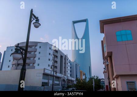 Ein Panoramablick auf Riad's ikonischen Kingdom Center Tower, umgeben von moderner urbaner Architektur, belebten Straßen und einem klaren blauen Himmel. Stockfoto