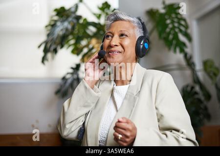 Professionelle Frau im Headset, die sich mit einem Anruf beschäftigt und Selbstvertrauen und positives Verhalten zum Ausdruck bringt Stockfoto