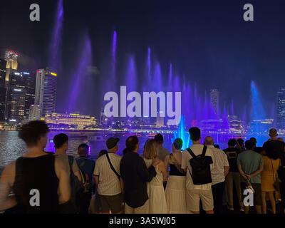 Spectra ist eine abendliche Licht- und Wassershow im Marina Bay Sands, Singapur. Die Leute schauen sich die Lichtshow an. Stockfoto