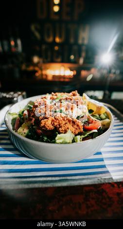 Eine Schüssel Essen mit viel Fleisch und Gemüse. Die Schüssel befindet sich auf einem Tablett und wird auf einen Tisch gestellt Stockfoto