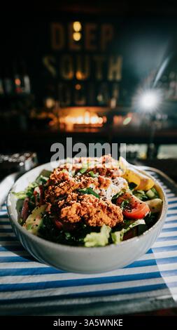 Eine Schüssel Essen mit viel Gemüse und Fleisch. Die Schüssel steht auf einem Tisch vor einem Kamin Stockfoto