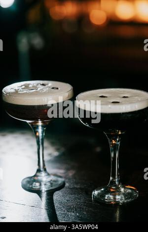 Zwei Gläser Mixgetränke stehen auf einem Tisch, von denen eines fast leer ist. Die andere ist fast voll, mit einer kleinen Menge Flüssigkeit. Das Glas Stockfoto