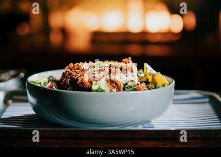 Eine Schüssel Essen mit viel Fleisch und Gemüse. Die Schüssel befindet sich auf einem Tablett. Das Tablett liegt auf einem Tisch Stockfoto