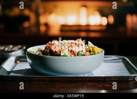 Eine Schüssel Essen mit viel Fleisch und Gemüse. Die Schüssel befindet sich auf einem Tablett. Das Tablett liegt auf einem Tisch Stockfoto