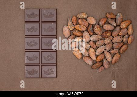 Schokoladenriegel. Das Herz besteht aus Kakaobohnen. Schokoladenherstellung von Bohnen bis Tassen. Monochrombraune Farbe. Stockfoto