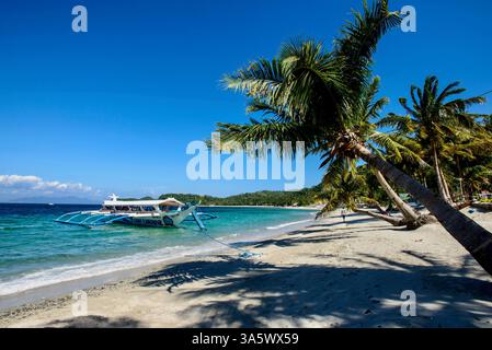 Ein Mann spaziert entlang des malerischen Talipanan Beach in Puerto Galera auf Mindoro Island, den Philippinen Stockfoto