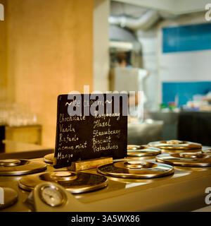 Ein handwerkliches Eisdiele mit verschiedenen Geschmacksrichtungen auf einem Tafel-Menü. Edelstahlbehälter mit Deckel für das Eis. Stockfoto