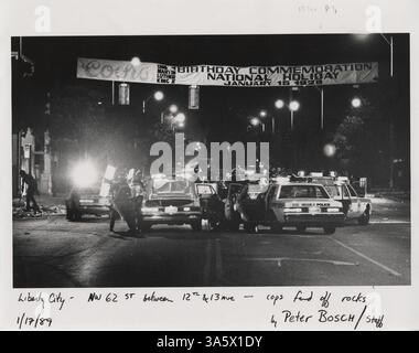 17. Januar 1989 - Miami, FL, USA - unter einem Martin Luther King-Feiertagsbanner in Liberty City wehren Offiziere im Januar 1989 Steine auf der Northeast 62nd Street zwischen 12th und 13th Avenue ab. Die Stadt wurde von Unruhen nach der Erschießung eines schwarzen Motorradfahrers durch den Polizeibeamten William Lozano aus Miami verzehrt. (Bild: © Peter Bosch/TNS/ZUMA Wire) Stockfoto