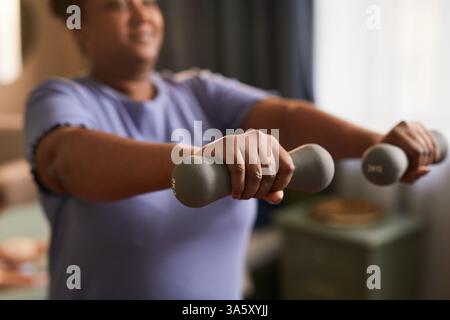 Nahaufnahme von afroamerikanischer Frau, die mit Kurzhanteln zu Hause während des Gewichtsverlust-Trainings arbeitet, Kopierraum Stockfoto