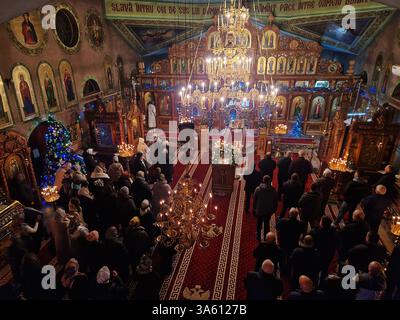 UNGHENI, MOLDAWIEN - 6. JANUAR 2025 Menschen beten in einer christlich-orthodoxen Kirche während des Gottesdienstes mit dem Priester, der Gebete vor der Kirche liest Stockfoto