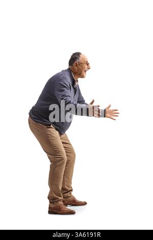 In voller Länge Profilaufnahme eines glücklichen reifen Mannes, der mit isolierten Händen auf weißem Hintergrund gestikuliert Stockfoto