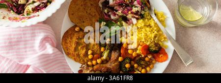 Ein nahrhaftes, herzhaftes Frühstück mit Linsenzucchini-Pfannkuchen, Hirse, gebackenem Hähnchenhals, gebratenen Süßkartoffeln, Brokkoli, Karotten, Kichererbsen, mit einem F Stockfoto