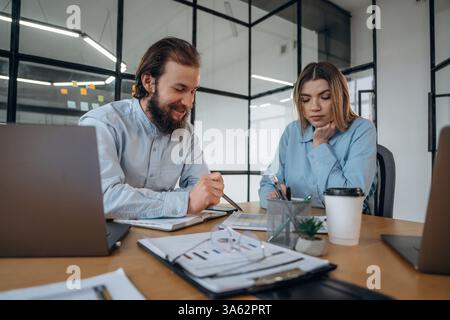 Freundliche Atmosphäre, eine Tasse Kaffee und Laptops. Mann und Frau sind zusammen im Büro. Stockfoto
