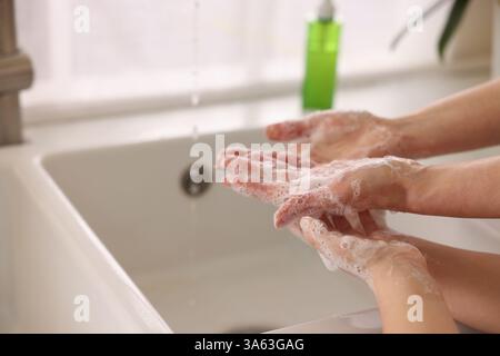 Mutter und Tochter waschen sich drinnen die Hände, Nahaufnahme Stockfoto