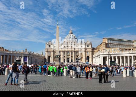 Touristen warten auf dem Petersplatz rund um den Vatikanischen Obelisken mit dem Petersdom (Basilica di San Pietro) im Hintergrund, Rom, Italien. Stockfoto