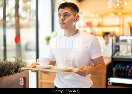 Ein Mann hält ein Tablett mit Kaffeetassen in der Hand Stockfoto