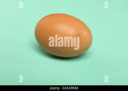 Ein Ei mit zerbrochener Schale auf türkisfarbenem Hintergrund, Nahaufnahme Stockfoto