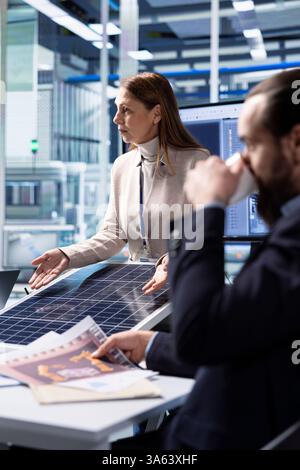 Produktionsleiter in der Photovoltaik-Fabrik, die sich Schaltpläne ansehen und Arbeiten auf der Betriebsfläche planen. Die Ingenieure von Solarpaneelen konstruieren Montagelinien und schauen sich die Pläne an Stockfoto