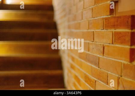 Die Backsteinwand im Raum wurde speziell vor dem Hintergrund einer Holztreppe mit Hintergrundbeleuchtung bearbeitet Stockfoto