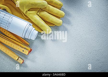 Sicherheitshandschuhe Blaupausen Holzmessgerät auf Betonhintergrund Gebäudekonzept Stockfoto